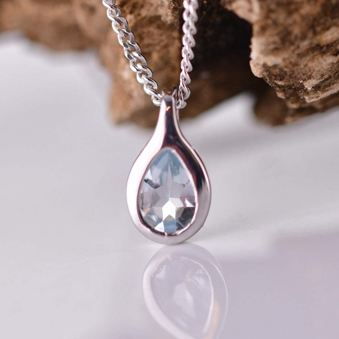 Aquamarine rubover pear pendant sterling silver on branch