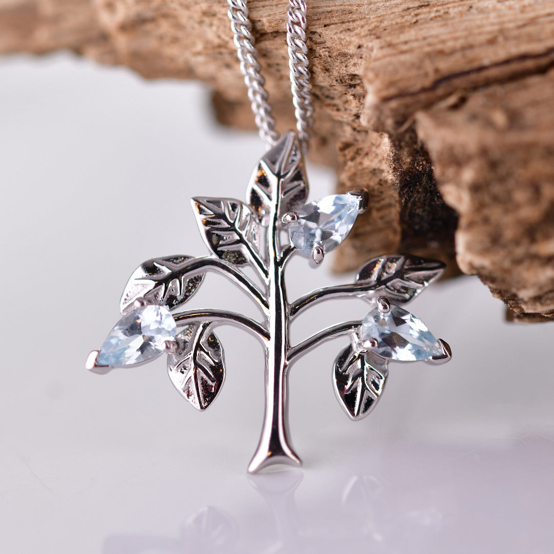 Aquamarine Tree of life necklace sterling silver resting on wooden branch